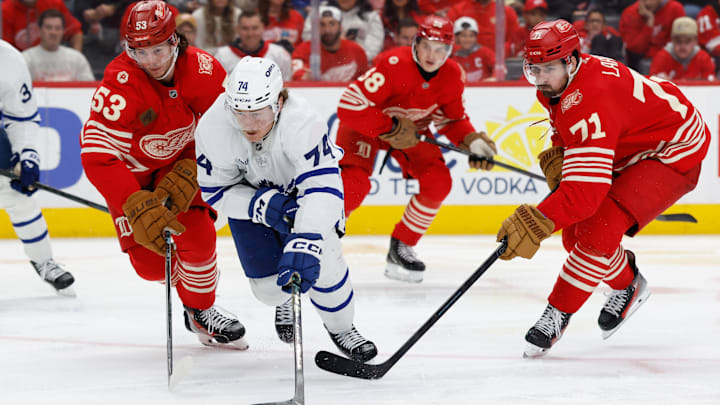 Dec 28, 2025; Detroit, Michigan, USA;  Toronto Maple Leafs center Bobby McMann (74) skates with the puck defended by Detroit Red Wings defenseman Moritz Seider (53) and center Dylan Larkin (71) in the third period at Little Caesars Arena. Mandatory Credit: Rick Osentoski-Imagn Images