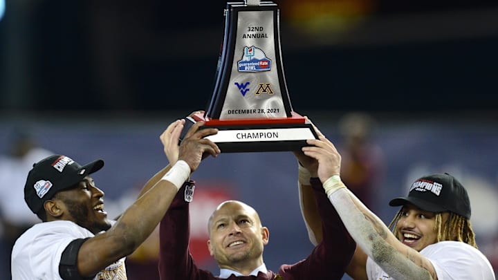 Dec 28, 2021; Phoenix, AZ, USA; Minnesota Golden Gophers head coach P. J. Fleck (center) celebrates with the trophy alongside players Tyler Nubin (left) and Ky Thomas (right) after defeating the West Virginia Mountaineers at Chase Field. Mandatory Credit: Joe Camporeale-Imagn Images Dec 28, 2021; Phoenix, AZ, USA; Minnesota Golden Gophers head coach P. J. Fleck (center) celebrates with the trophy alongside players Tyler Nubin (left) and Ky Thomas (right) after defeating the West Virginia Mountaineers at Chase Field. Mandatory Credit: Joe Camporeale-Imagn Images