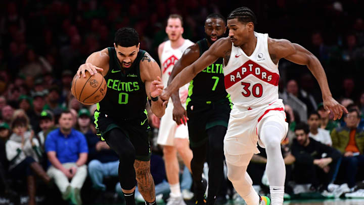 Dec 31, 2024; Boston, Massachusetts, USA;  Boston Celtics forward Jayson Tatum (0) controls the ball while Toronto Raptors guard Ochai Agbaji (30) defends during the first half at TD Garden. Mandatory Credit: Bob DeChiara-Imagn Images