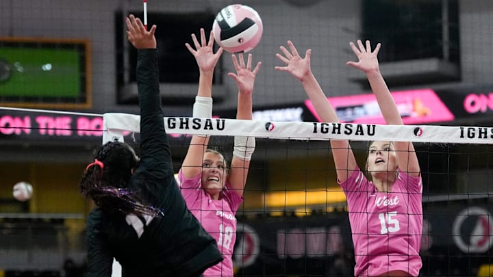 Iowa City West's Josephine Austen (18) and Audrey Small (15) defend an attack by Ankeny Centennial's Adilyne Reyes (11) Nov. 3, 2025 during the Class 5A Iowa high school state volleyball quarterfinals at Xtream Arena in Coralville, Iowa.