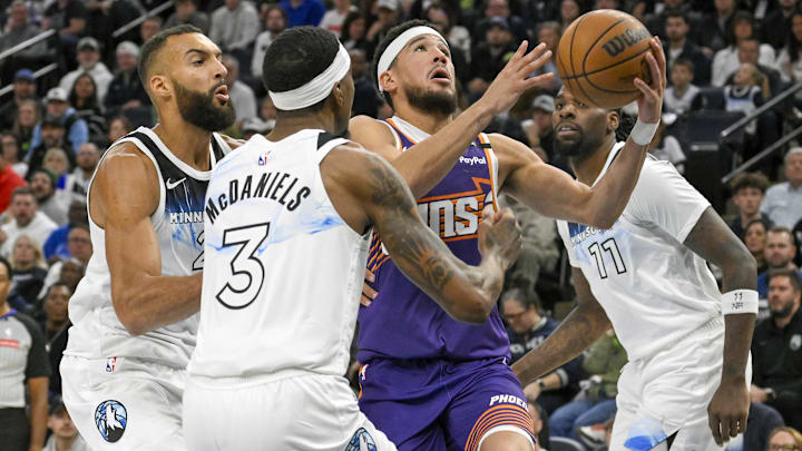 Phoenix Suns guard Devin Booker cuts through Minnesota Timberwolves center Rudy Gobert, forward Jaden McDaniels (3) and center Naz Reid (11) for a layup during the second quarter at Target Center in Minneapolis on Nov. 17, 2024.