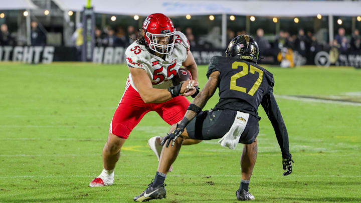 Nov 29, 2024; Orlando, Florida, USA; UCF Knights offensive lineman Cameron Kinnie (55) carries the ball against UCF Knights defensive back Chasen Johnson (27) during the second quarter at FBC Mortgage Stadium. Mandatory Credit: Mike Watters-Imagn Images