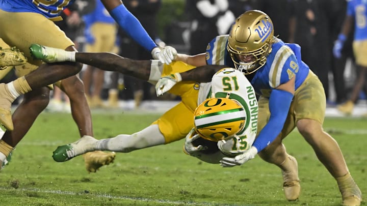 Oregon Ducks wide receiver Tez Johnson sent flying through the air as UCLA Bruins linebacker Carson Schwesinger makes the tackle.