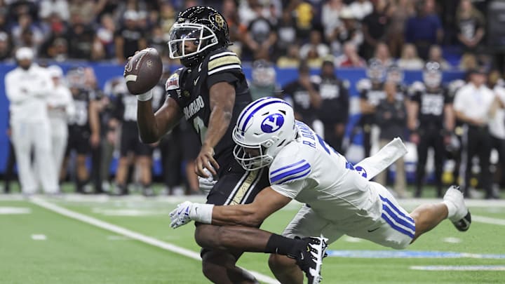 Colorado Buffaloes quarterback Shedeur Sanders is tackled by Brigham Young Cougars safety Raider Damuni during the Alamo Bowl.