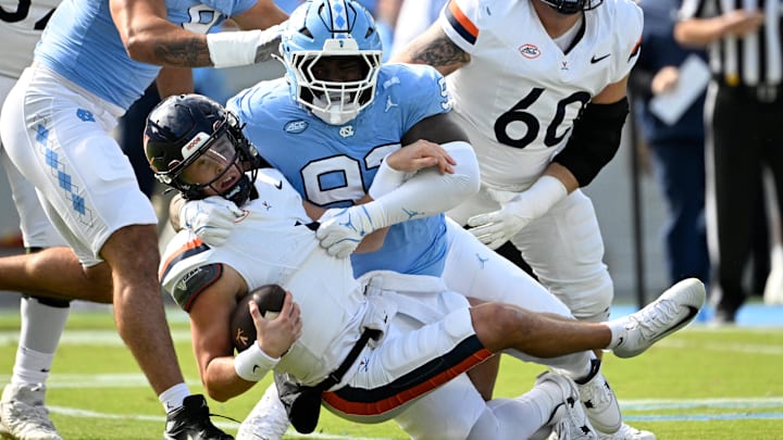 Oct 25, 2025; Chapel Hill, North Carolina, USA; Virginia Cavaliers quarterback Chandler Morris (4) is sacked by North Carolina Tar Heels defensive lineman CJ Mims (92) in the first quarter at Kenan Stadium. Mandatory Credit: Bob Donnan-Imagn Images
