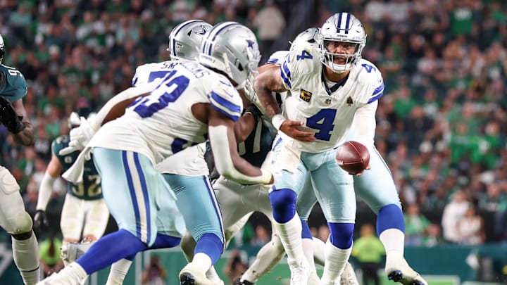 Dallas Cowboys quarterback Dak Prescott hands the ball to running back Javonte Williams.