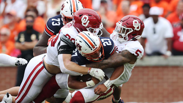 Sep 28, 2024; Auburn, Alabama, USA;  Auburn Tigers running back Jarquez Hunter (27) is tackled by Oklahoma Sooners defensive lineman Caiden Woullard (90) and defensive back Woodi Washington (5) during the second quarter at Jordan-Hare Stadium. Mandatory Credit: John Reed-Imagn Images