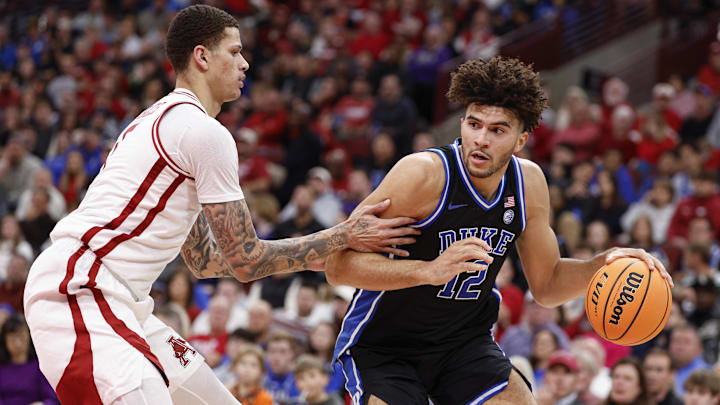 Nov 27, 2025; Chicago, Illinois, USA; Duke Blue Devils forward Cameron Boozer (12) drives to the basket against Arkansas Razorbacks forward Trevon Brazile (7) during the second half at United Center. Mandatory Credit: Kamil Krzaczynski-Imagn Images