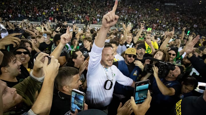 Coach Dan Lanning celebrates amid a crowd of fans on the field as No. 3 Oregon knocked off No. 2 Ohio State 32-31 on Saturday at Autzen Stadium in Eugene, Ore.