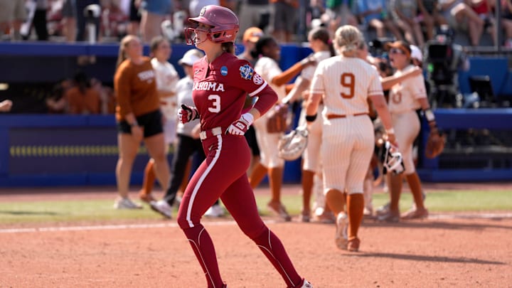 Oklahoma outfielder Chaney Helton walks off the field as Texas celebrates its win at the WCWS.