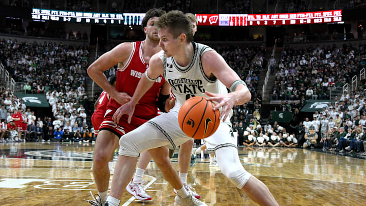  Mar 2, 2025; East Lansing, Michigan, USA;  Michigan State Spartans forward Jaxon Kohler (0) moves the ball down the baseline against Wisconsin Badgers forward Carter Gilmore (7) during the second half at Jack Breslin Student Events Center. Mandatory Credit: Dale Young-Imagn Images