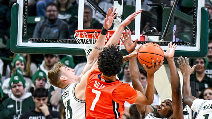 Illinois' Will Riley, center, scores despite the defensive effort of Michigan State's Carson Cooper, left, and Tre Holloman, right, during the first half on Sunday, Jan. 19, 2025, at the Breslin Center in East Lansing.