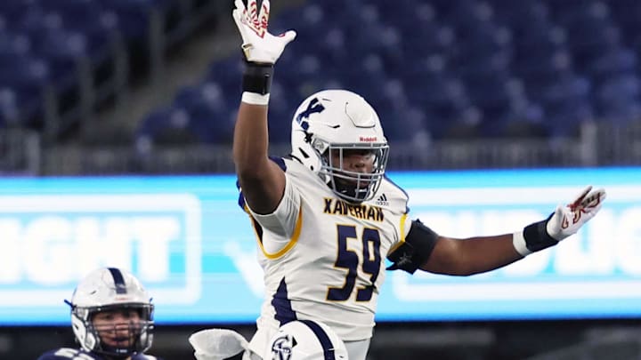 Xaverian linemen Micah Amedee pressures St. John's Prep quarterback Riley Selvais in the second quarter during the Division 1 state title game at Gillette Stadium on Wednesday, Nov. 29, 2023.