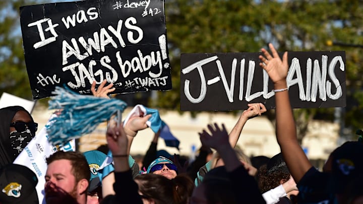 Jaguars fan Eric Hall holds his signs as he joins other fans outside TIAA Bank Field to cheer.