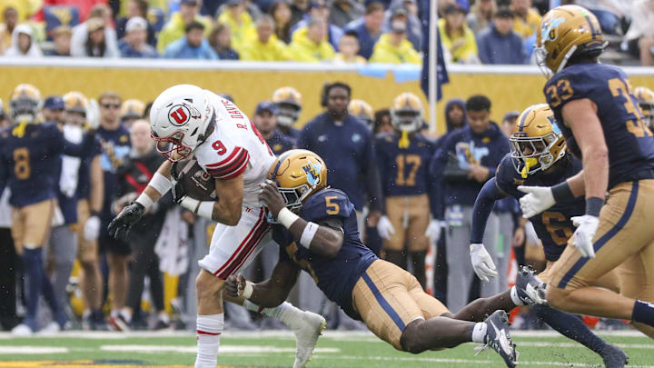 Sep 27, 2025; Morgantown, West Virginia, USA; Utah Utes wide receiver Ryan Davis (9) makes a catch and shakes a tackle from West Virginia Mountaineers safety Fred Perry (5) during the second quarter at Milan Puskar Stadium. Mandatory Credit: Ben Queen-Imagn Images