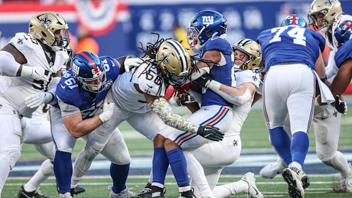 Dec 8, 2024; East Rutherford, New Jersey, USA; New York Giants running back Tyrone Tracy Jr. (29) is tackled by New Orleans Saints linebacker Demario Davis (56) and linebacker Pete Werner (20) during the second half at MetLife Stadium. Mandatory Credit: Vincent Carchietta-Imagn Images