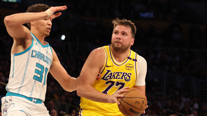 Feb 19, 2025; Los Angeles, California, USA; Los Angeles Lakers guard Luka Doncic (77) drives against Charlotte Hornets forward Tidjane Salaun (31) during the second quarter at Crypto.com Arena. Mandatory Credit: Jason Parkhurst-Imagn Images