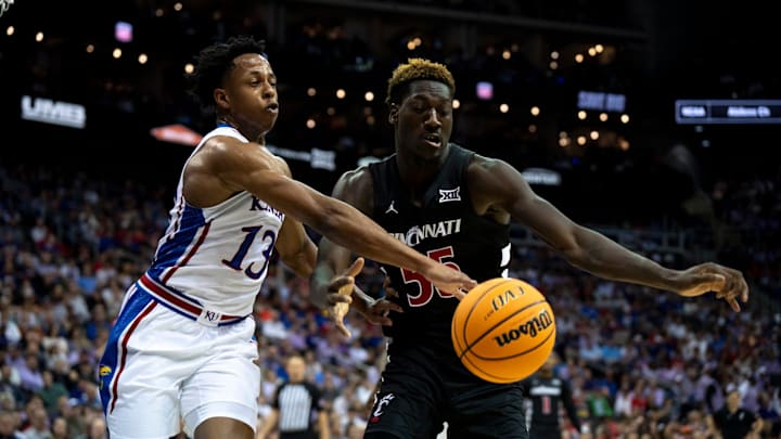 Kansas Jayhawks guard Elmarko Jackson (13) and Cincinnati Bearcats forward Aziz Bandaogo (55) compete for a rebound in the first half of the Big 12 Conference tournament game between Cincinnati Bearcats and Kansas Jayhawks at T-Mobile Center in Kansas City, Mo., on Wednesday, March 13, 2024.