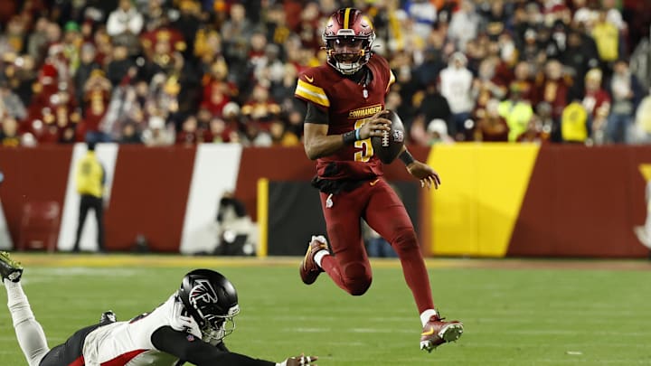 Washington Commanders quarterback Jayden Daniels (5) runs with the ball as Atlanta Falcons tight end Kyle Pitts (8) attempts a tackle during the third quarter at Northwest Stadium. 