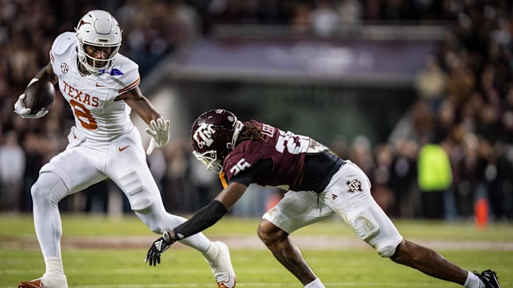 Nov 30, 2024; College Station, Texas, USA; Texas Longhorns tight end Amari Niblack (8) runs with the ball, bracing for a tackle from Texas A&M Aggies defensive back Will Lee III (26) in the second quarter of the Lone Star Showdown game at Kyle Field. Mandatory Credit: Sara Diggins/USA TODAY Network via Imagn Images