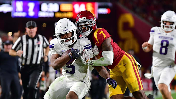 Nov 7, 2025; Los Angeles, California, USA; Northwestern Wildcats running back Caleb Komolafe (5) runs the ball against Southern California Trojans safety Kamari Ramsey (7) during the first half at the Los Angeles Memorial Coliseum. Mandatory Credit: Gary A. Vasquez-Imagn Images