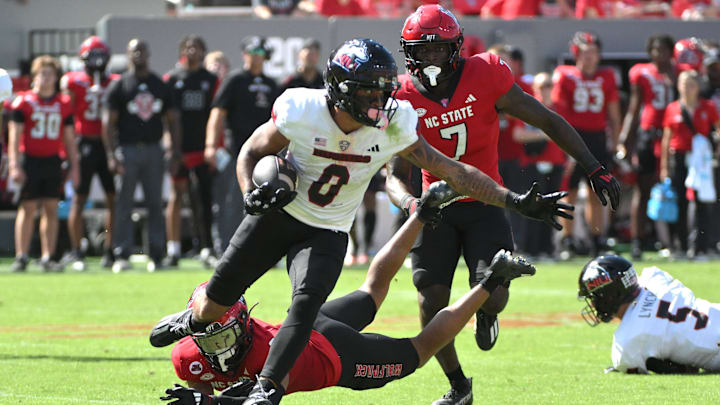 Sep 28, 2024; Raleigh, North Carolina, USA; Northern Illinois Huskies wide receiver Cam Thompson (0) eludes North Carolina State Wolfpack cornerback Brandon Cisse (2) at Carter-Finley Stadium. Mandatory Credit: Zachary Taft-Imagn Images