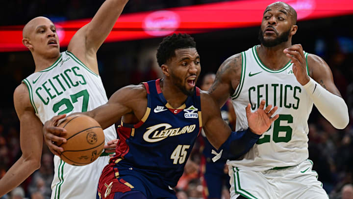 Nov 30, 2025; Cleveland, Ohio, USA; Cleveland Cavaliers guard Donovan Mitchell (45) drives on Boston Celtics forward Xavier Tillman (26) and guard Jordan Walsh (27) during the second half at Rocket Arena. Mandatory Credit: David Dermer-Imagn Images