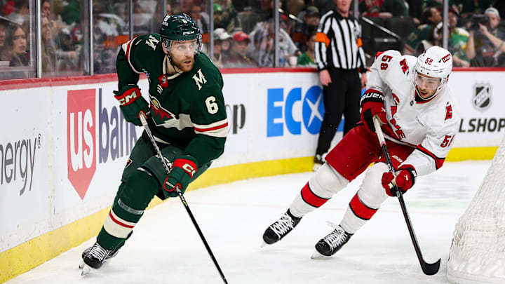 Feb 27, 2024; Saint Paul, Minnesota, USA; Minnesota Wild defenseman Dakota Mermis (6) skates with the puck alongside Carolina Hurricanes left wing Michael Bunting (58) during the second period at Xcel Energy Center. Mandatory Credit: Matt Krohn-Imagn Images