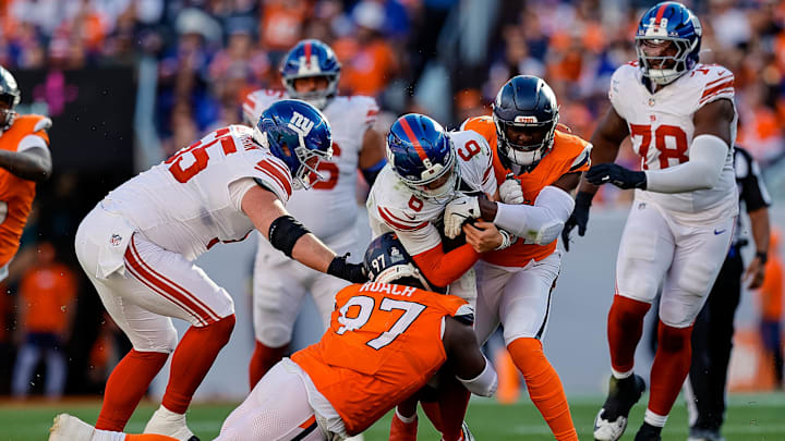 Oct 19, 2025; Denver, Colorado, USA; New York Giants quarterback Jaxson Dart (6) is tackled by Denver Broncos defensive tackle Malcolm Roach (97) and linebacker Que Robinson (51) as New York Giants guard Austin Schlottmann (65) and offensive tackle Andrew Thomas (78) defend in the third quarter at Empower Field at Mile High.  