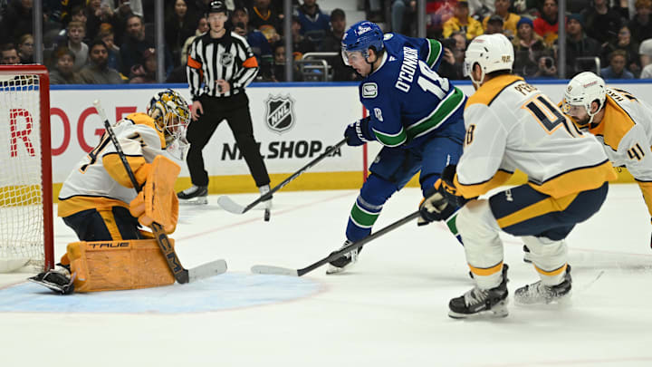 Mar 12, 2026; Vancouver, British Columbia, CAN; Vancouver Canucks left wing Drew O'Connor (18) shoots the puck against Nashville Predators goaltender Juuse Saros (74) during the second period at Rogers Arena. Mandatory Credit: Simon Fearn-Imagn Images