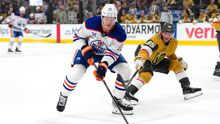 May 8, 2025; Las Vegas, Nevada, USA; Edmonton Oilers center Trent Frederic (21) keeps the puck away from Vegas Golden Knights right wing Victor Olofsson (95) during the first period of game two of the second round of the 2025 Stanley Cup Playoffs at T-Mobile Arena. Mandatory Credit: Stephen R. Sylvanie-Imagn Images