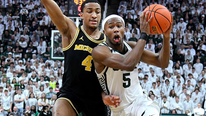 Mar 9, 2025; East Lansing, Michigan, USA;  Michigan State Spartans guard Tre Holloman (5) drives past Michigan Wolverines guard Nimari Burnett (4) to the basket during the second half at Jack Breslin Student Events Center. Mandatory Credit: Dale Young-Imagn Images