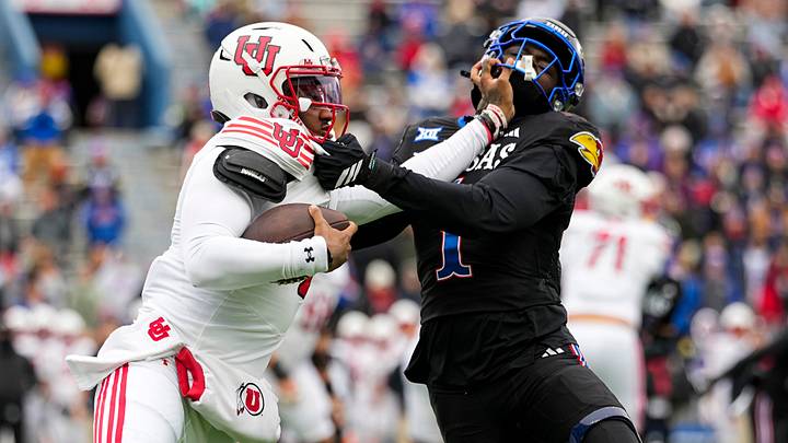 Nov 28, 2025; Lawrence, Kansas, USA; Utah Utes quarterback Devon Dampier (4) stiff arms Kansas Jayhawks linebacker Bangally Kamara (1) during the second half at David Booth Kansas Memorial Stadium. Mandatory Credit: Jay Biggerstaff-Imagn Images Nov 28, 2025; Lawrence, Kansas, USA; Utah Utes quarterback Devon Dampier (4) stiff arms Kansas Jayhawks linebacker Bangally Kamara (1) during the second half at David Booth Kansas Memorial Stadium. Mandatory Credit: Jay Biggerstaff-Imagn Images