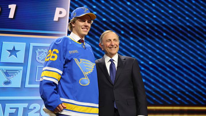 Jun 26, 2026; Buffalo, New York, USA; Tynan Lawrence poses beside NHL commissioner Gary Bettman after being selected with the eleventh pick in the first round of the 2026 NHL Draft by the St. Louis Blues at KeyBank Center. Mandatory Credit: Timothy T. Ludwig-Imagn Images