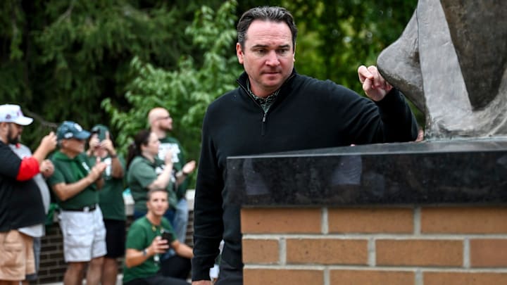Michigan State's head coach Jonathan Smith throws a penny at the foot of the Sparty statue before the start of the football game against Ohio State on Saturday, Sept. 28, 2024, on his way to Spartan Stadium in East Lansing.