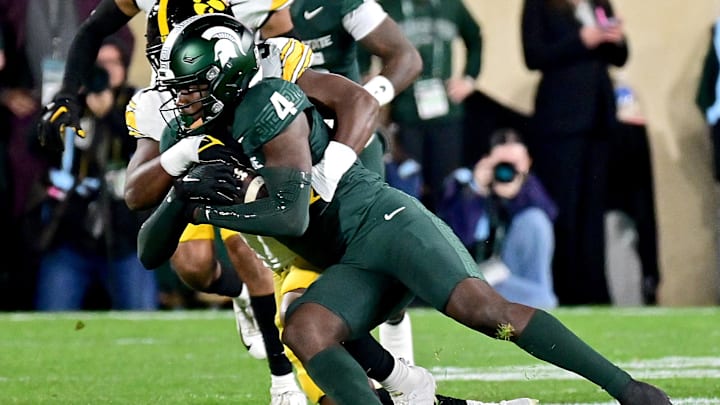 Oct 19, 2024; East Lansing, Michigan, USA;  Iowa Hawkeyes linebacker Jay Higgins (34) tackles Michigan State Spartans wide receiver Jaron Glover (4) after a first down catch in the first quarter at Spartan Stadium. Mandatory Credit: Dale Young-Imagn Images