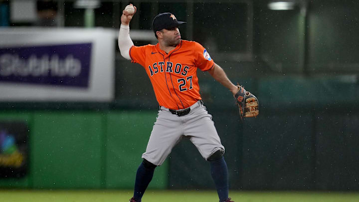 Houston Astros infielder Jose Altuve throws a ball to first base, wearing an orange jersey and a dark blue hat. 
