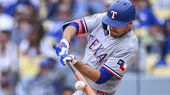 Texas Rangers batter Evan Carter swings his bat at a baseball. 