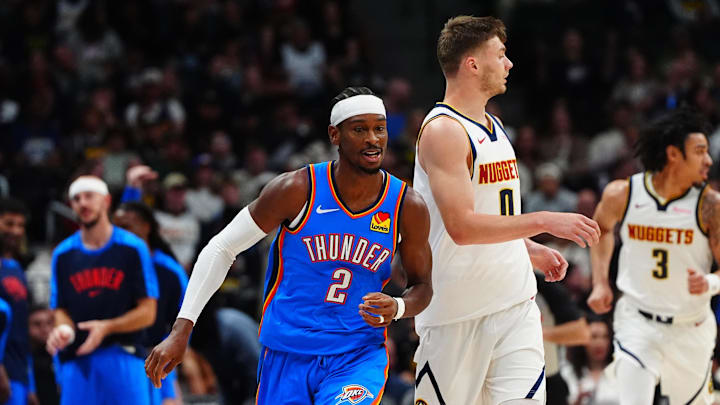 Oct 15, 2024; Denver, Colorado, USA; Oklahoma City Thunder guard Shai Gilgeous-Alexander (2) and Denver Nuggets guard Christian Braun (0) during the first quarter at Ball Arena. Mandatory Credit: Ron Chenoy-Imagn Images