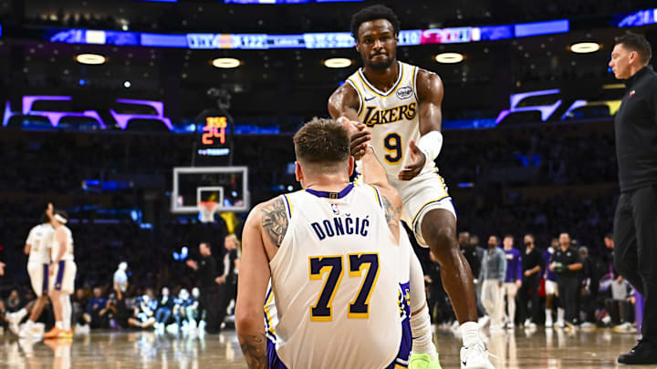 Nov 2, 2025; Los Angeles, California, USA; Los Angeles Lakers guard Bronny James (9) helps guard Luka Doncic (77) up from the floor against the Miami Heat during the second half at Crypto.com Arena. Mandatory Credit: Jonathan Hui-Imagn Images