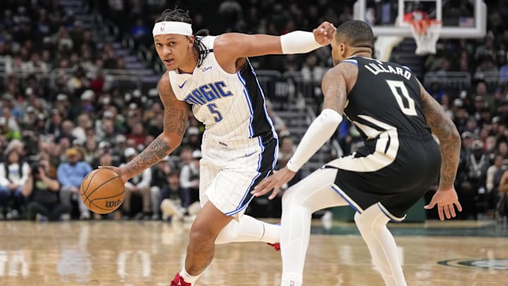 Orlando Magic forward Paolo Banchero (5) drives with the ball as Milwaukee Bucks guard Damian Lillard (0) defends during the fourth quarter at Fiserv Forum.