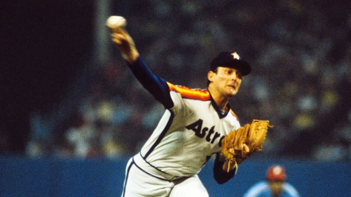 Former Houston Astros pitcher Nolan Ryan throws a pitch wearing a white jersey and navy blue hat. Former Houston Astros pitcher Nolan Ryan throws a pitch wearing a white jersey and navy blue hat.