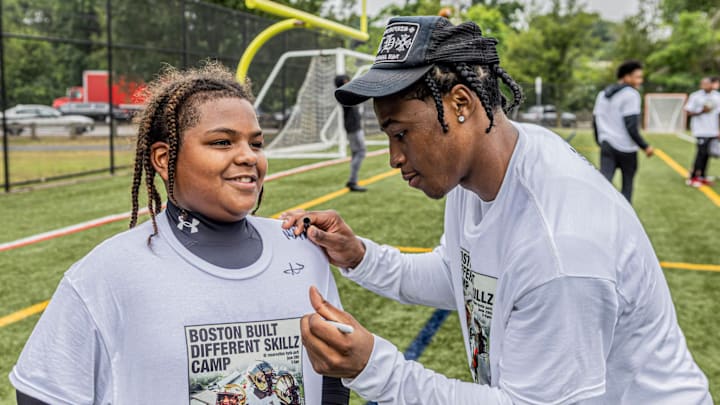 Boston College defensive back Max Tucker signs a young camper's shirt. 