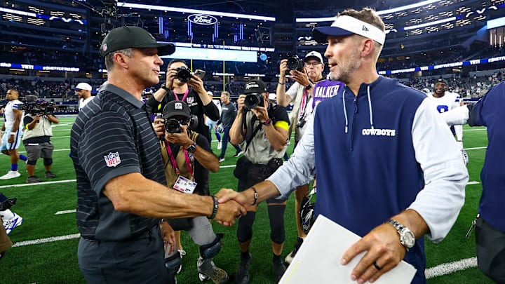 Dallas Cowboys head coach Brian Schottenheimer shakes hands with Baltimore Ravens head coach John Harbaugh.