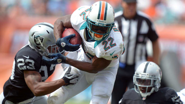 Miami Dolphins running back Reggie Bush (22) eludes Oakland Raiders cornerback Joseph Hanson (23) and linebacker Roland McClain (55) to score on a 23-yard touchdown run at Sun Life Stadium in 2012. Miami Dolphins running back Reggie Bush (22) eludes Oakland Raiders cornerback Joseph Hanson (23) and linebacker Roland McClain (55) to score on a 23-yard touchdown run at Sun Life Stadium in 2012.