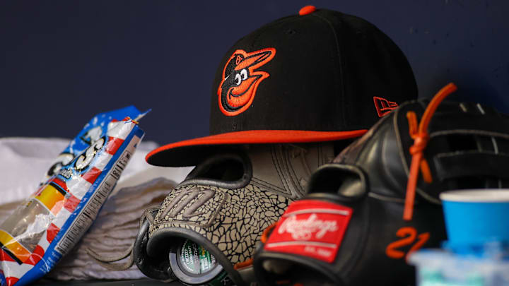 A detailed view of a Baltimore Orioles hat and glove in the dugout