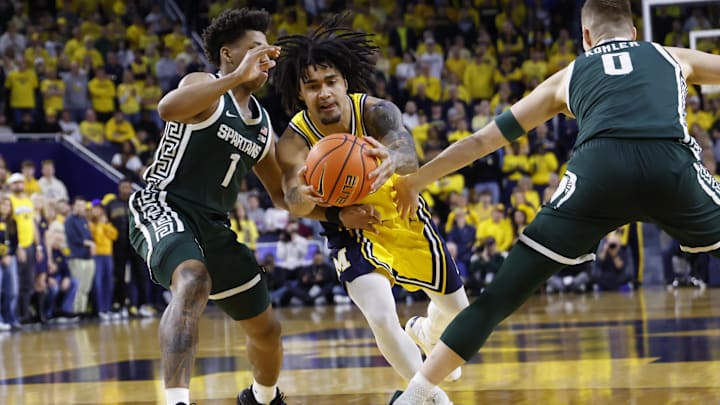 Mar 8, 2026; Ann Arbor, Michigan, USA; Michigan Wolverines guard Elliot Cadeau (3) dribbles defended by Michigan State Spartans guard Jeremy Fears Jr. (1) and forward Jaxon Kohler (0) in the first half at Crisler Center. Mandatory Credit: Rick Osentoski-Imagn Images Mar 8, 2026; Ann Arbor, Michigan, USA; Michigan Wolverines guard Elliot Cadeau (3) dribbles defended by Michigan State Spartans guard Jeremy Fears Jr. (1) and forward Jaxon Kohler (0) in the first half at Crisler Center. Mandatory Credit: Rick Osentoski-Imagn Images