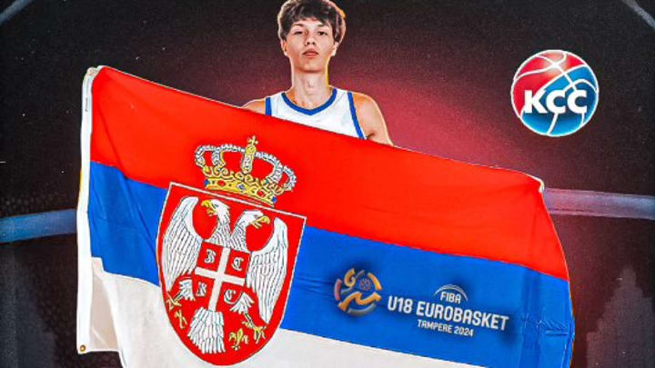 Niko Bundalo holds up a Serbian basketball banner. 