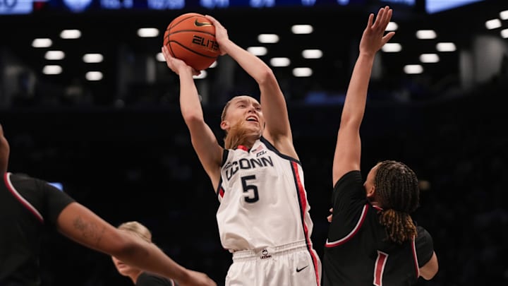Dec 7, 2024; Brooklyn, New York, USA; Connecticut Huskies guard Paige Bueckers (5) attempts a shot defended by Louisville Cardinals guard Imari Berry (1) during the first half at Barclays Center. Mandatory Credit: Lucas Boland-Imagn Images Dec 7, 2024; Brooklyn, New York, USA; Connecticut Huskies guard Paige Bueckers (5) attempts a shot defended by Louisville Cardinals guard Imari Berry (1) during the first half at Barclays Center. Mandatory Credit: Lucas Boland-Imagn Images