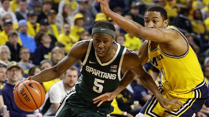 Feb 17, 2024; Ann Arbor, Michigan, USA;  Michigan State Spartans guard Tre Holloman (5) dribbles on Michigan Wolverines guard Nimari Burnett (4) in the second half at Crisler Center. Mandatory Credit: Rick Osentoski-Imagn Images